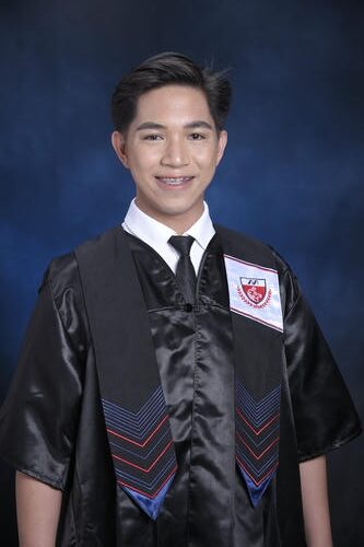 Young graduate smiling in a black gown with a red and white emblem set against a dark blue background