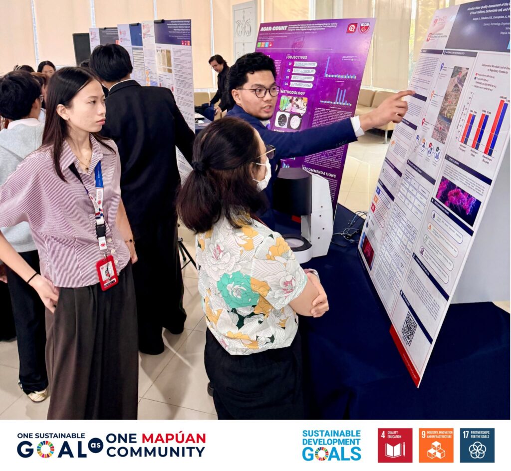 A student presenter walks evaluators through the research poster