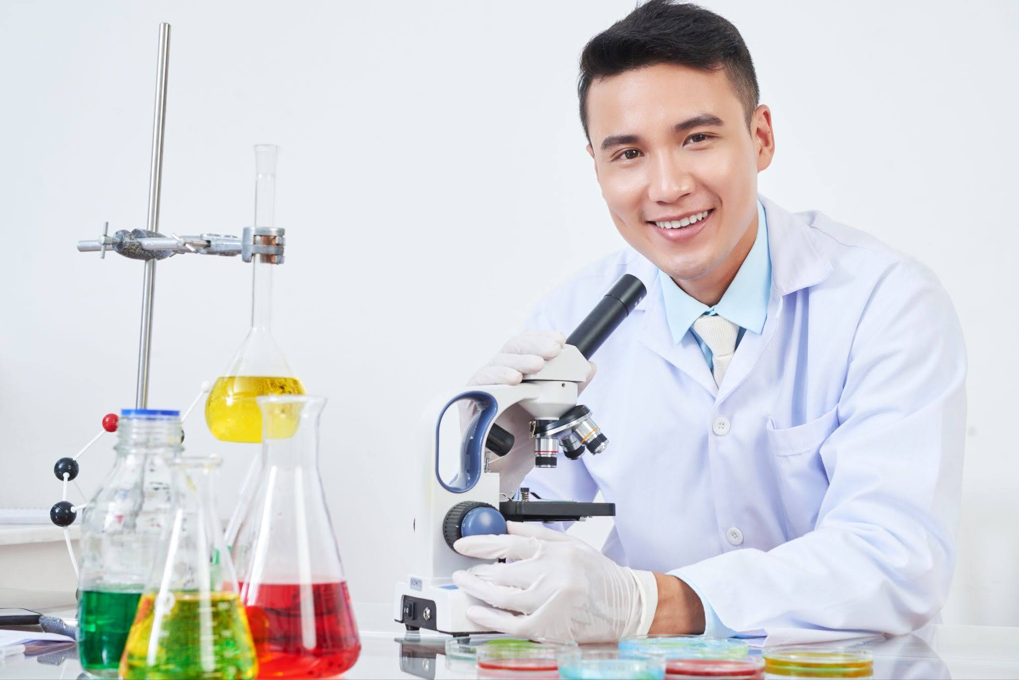 Smiling young male in science laboratory with microscope
