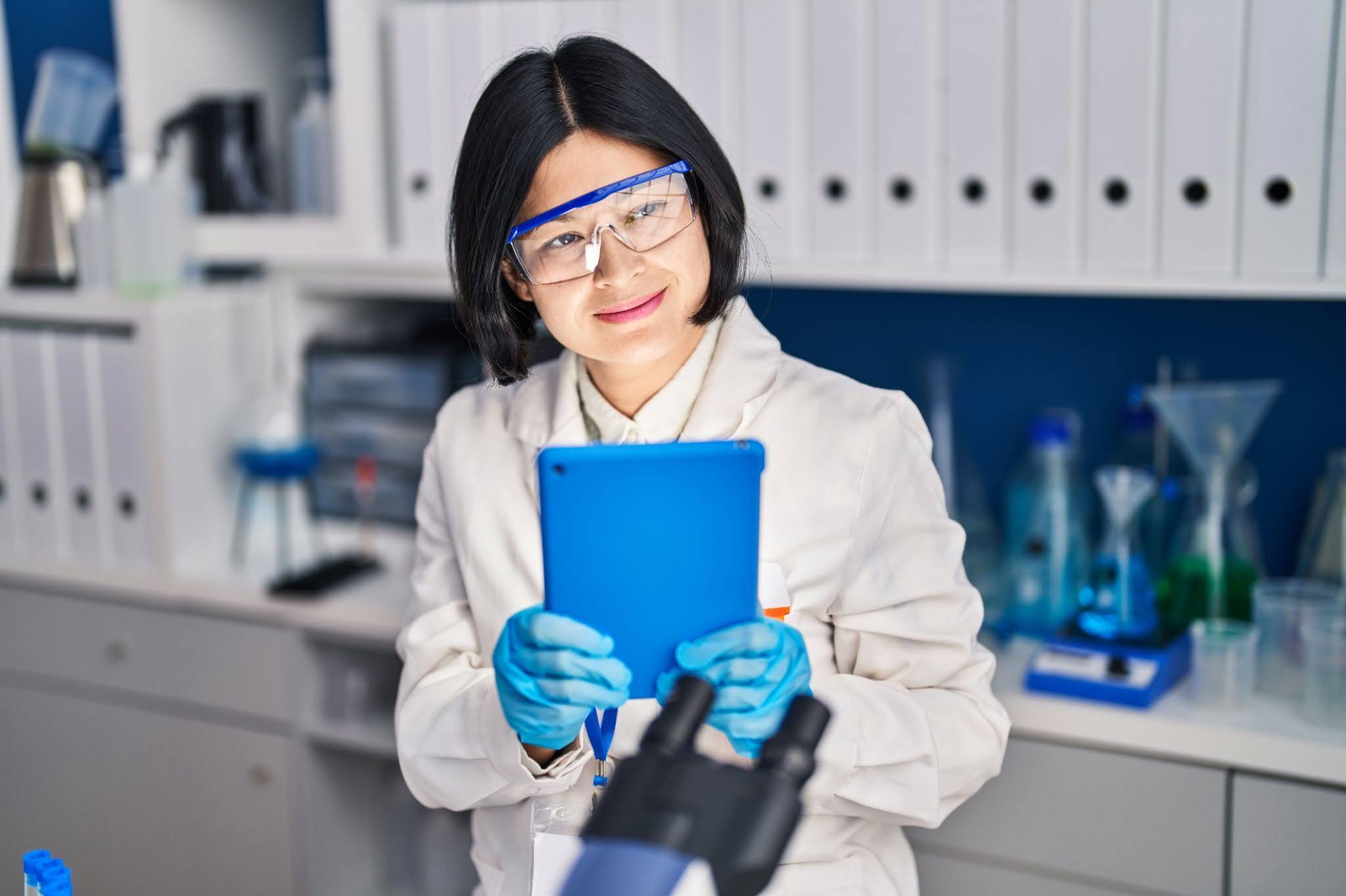 Young woman scientist using touchpad working at laboratory