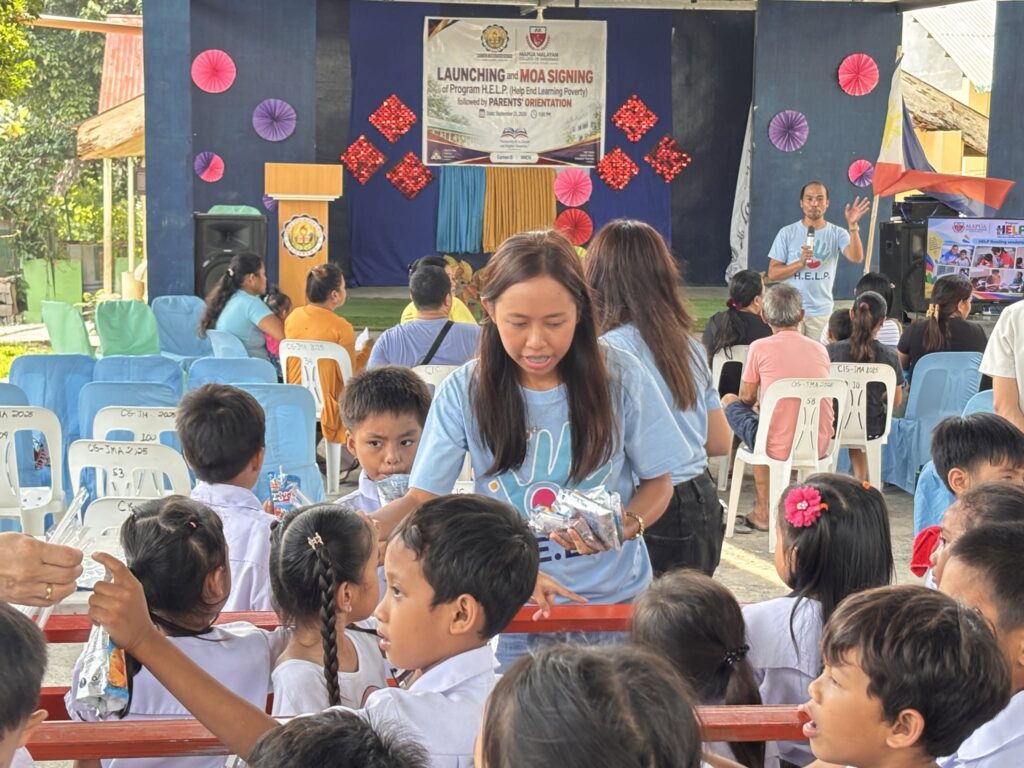 Blete mae s Dante a civil engineering alumna from the class of 2026 distributes food packs to grade 1 pupils of carmen integrated school