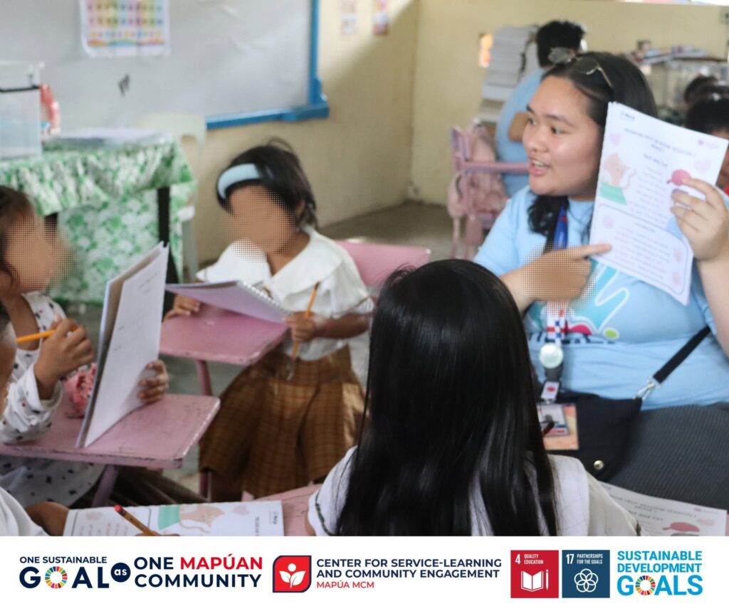 Alumni high school volunteer tasha therese g Baldonado points to an illustrated reading worksheet while guiding a small group of grade 1 pupils during program h E L P Session 1 at carmen integrated school